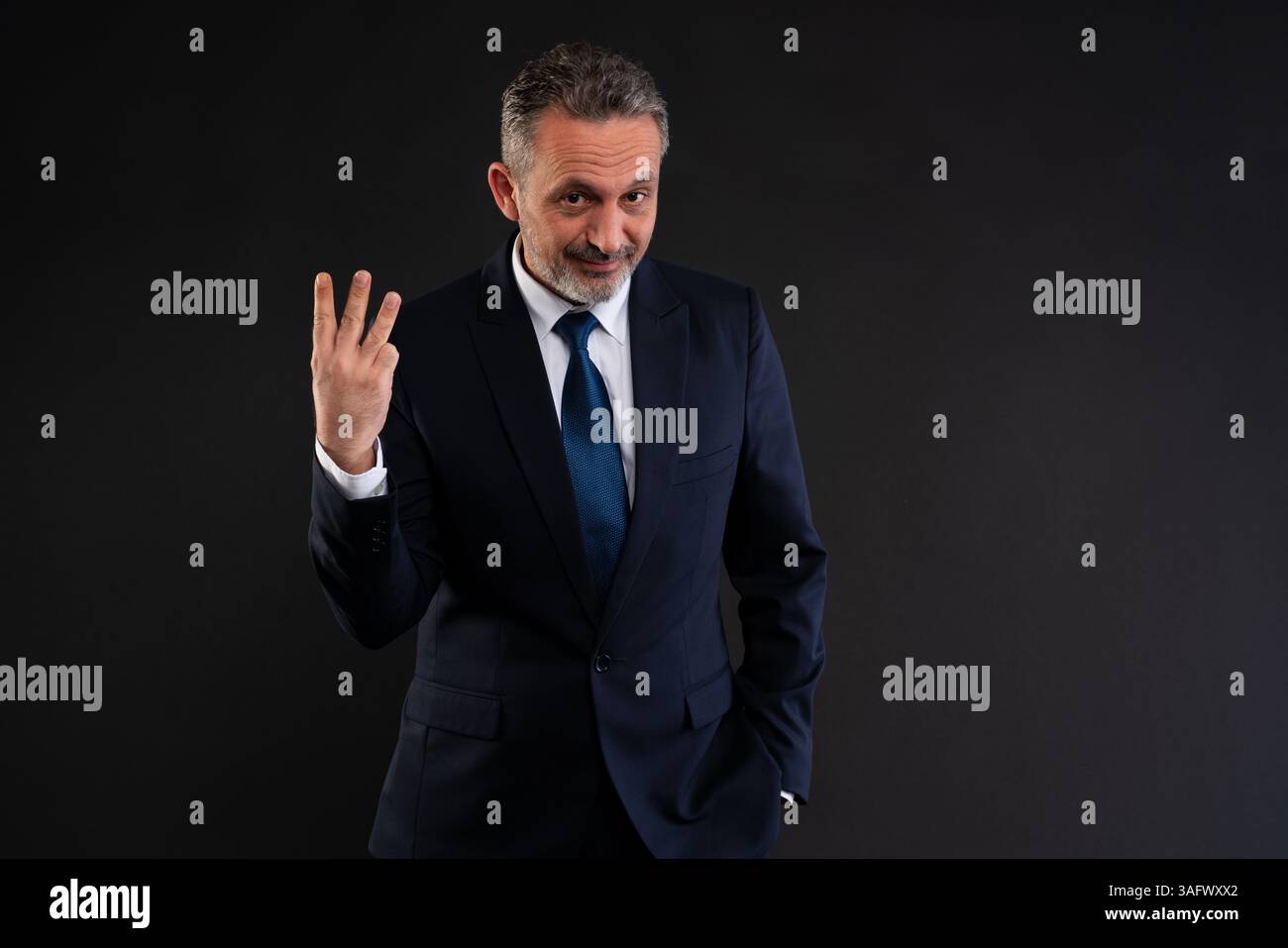 Mature businessman in a suit holding up three fingers, suggesting countdown, listing Stock Photo
