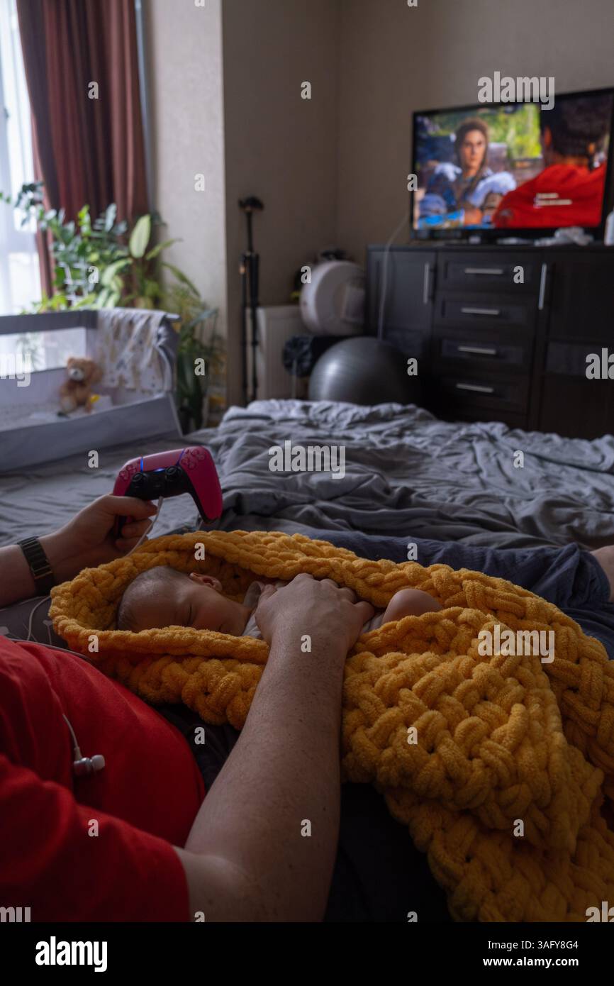 Cozy Moment father playing video games while Baby sleeping Stock Photo ...