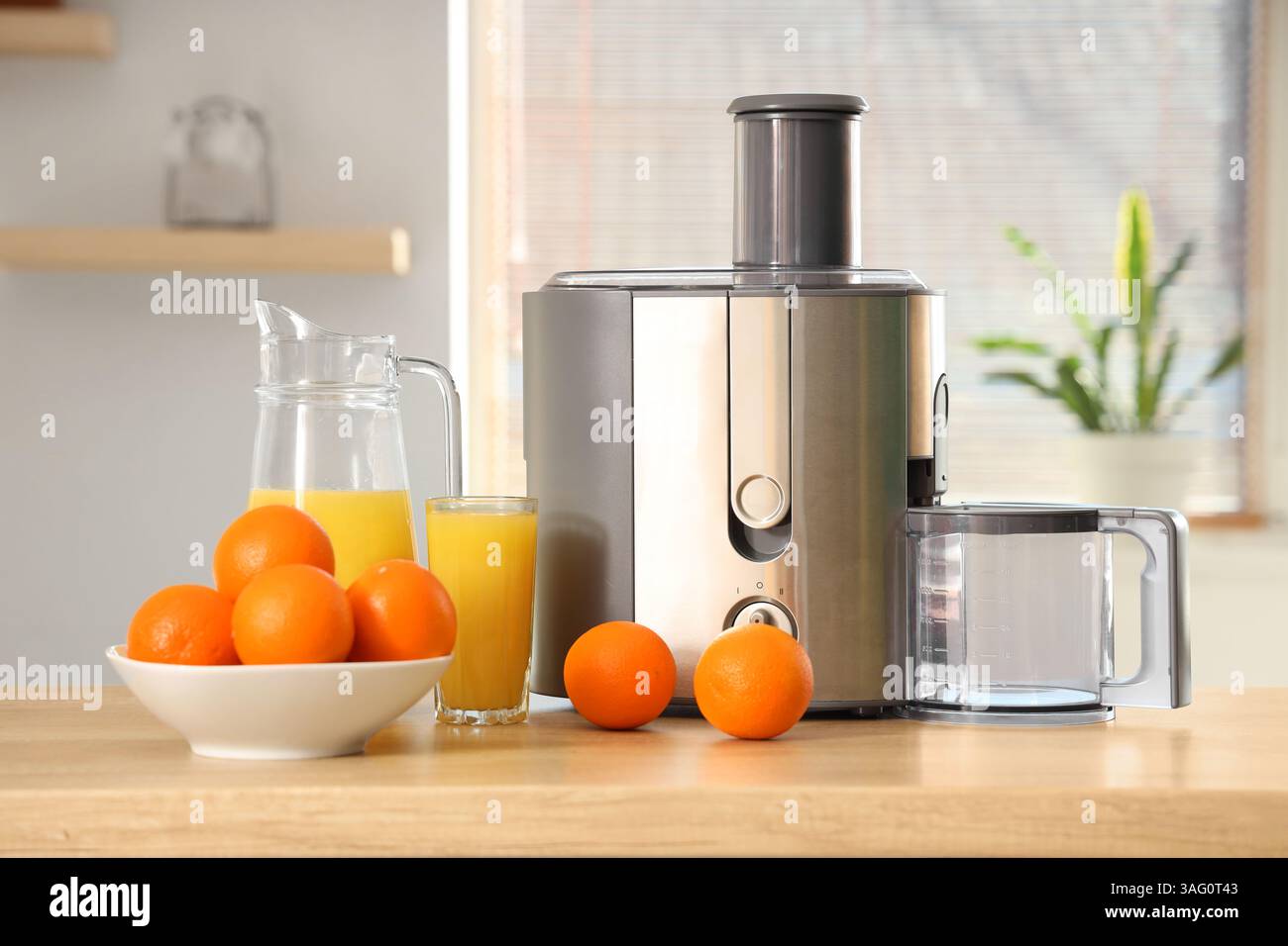 Modern juicer with oranges on table in kitchen Stock Photo