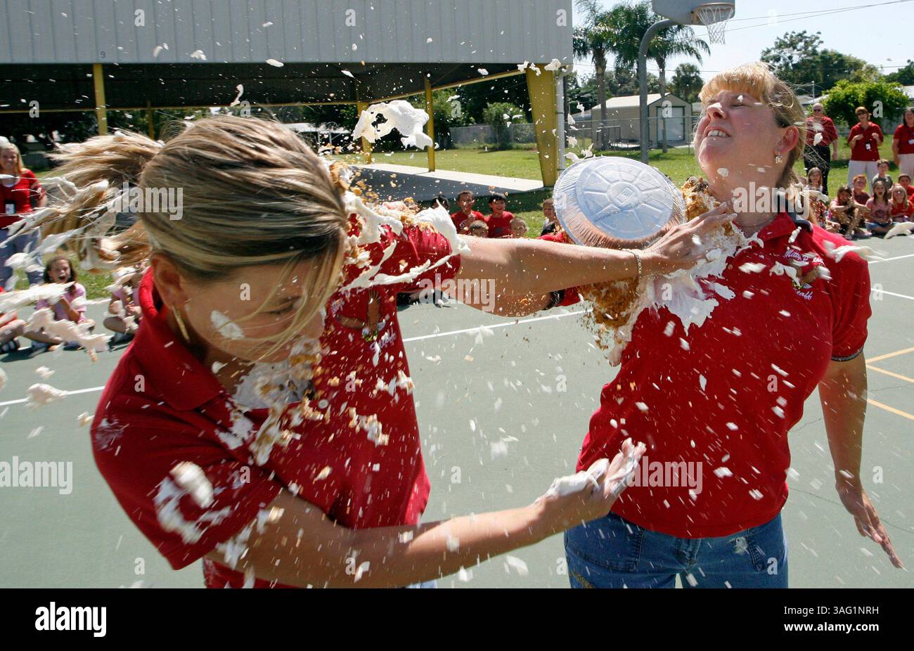 CAPTION: (New Port Richey 09/21/2007) Mittye P. Locke Elementary School Assistant Principal kara Merlin (cq), left and principal Tammy Berryhill (cq) hurl pies at each other on Friday afternoon 09/21/2007. They agreed last spring that if the students outperformed the 2006 FCAT scores they would have a pie fight for the grades that accomplished that challenge. On friday afternoon they fulfilled their promise and launched whipped cream and vanilla pudding pies at each other on the basketball court before a crowd of cheering 140 fifth graders. (MIKE PEASE | Times).STORY SUMMARY: .Mittye P. Locke Stock Photo