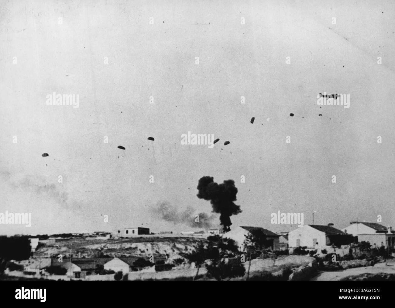 Crete: A German Troop ***** To Its Doom -- A cloud of smoke marks the place where the German troops carrier crashed, while parachute troops from another aircraft descent to meet the fire of the British troops. On Crete the German bombing of the ***** near Candia, was followed by 'ground strafing ***** Messerschmitts. While these fighters patrolled the bombed area,  troop-carrying aircraft followed in, escorted by bombers. Parachute troops, of whom 60-70 per cent were destroyed before reaching ground, were then dropped. These photographs show the shotting down in flames by A.A. gunfire of a Ger Stock Photo