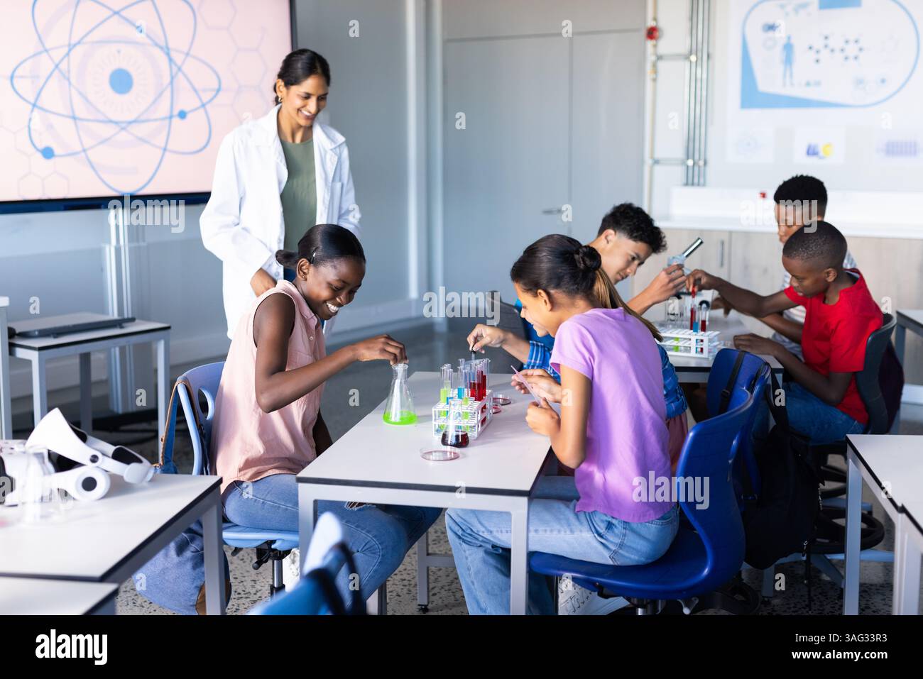 In school, students conducting science experiments with Indian female teacher in classroom Stock Photo