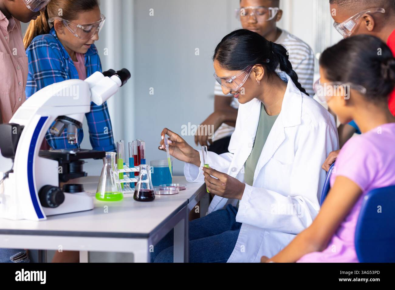 In school, students conducting science experiment with test tubes and microscope Stock Photo