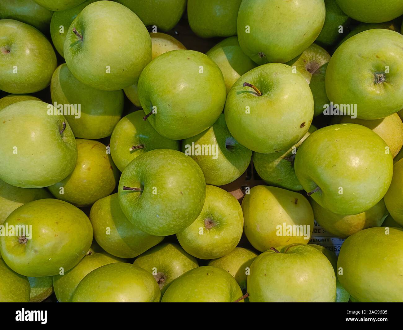 green apples stacked together. The apples are fresh, shiny, and smooth, showing different shades of green. These apples look juicy and healthy - Smartphone Captured Stock Image