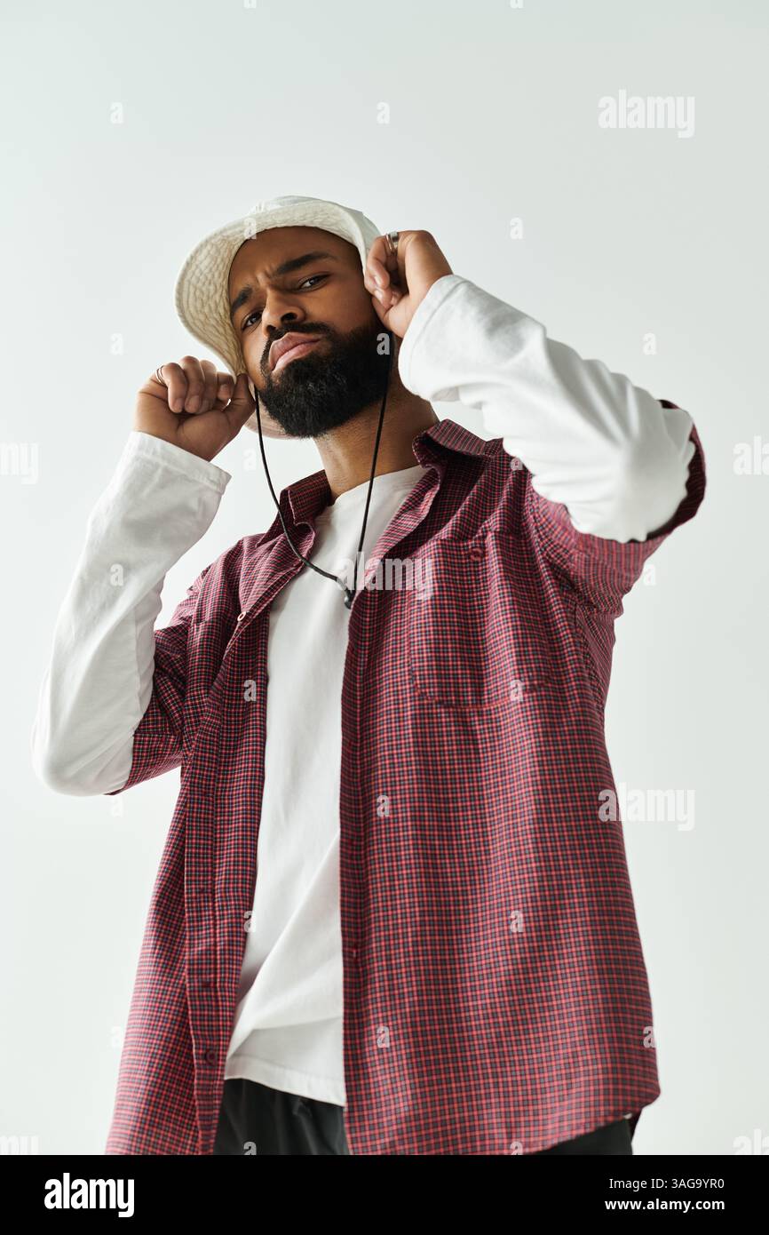 A stylish young man poses confidently, adjusting his headphones and ...