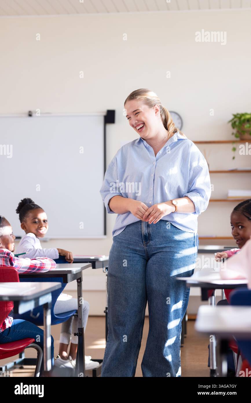 In school, female teacher smiling and engaging with diverse students in ...