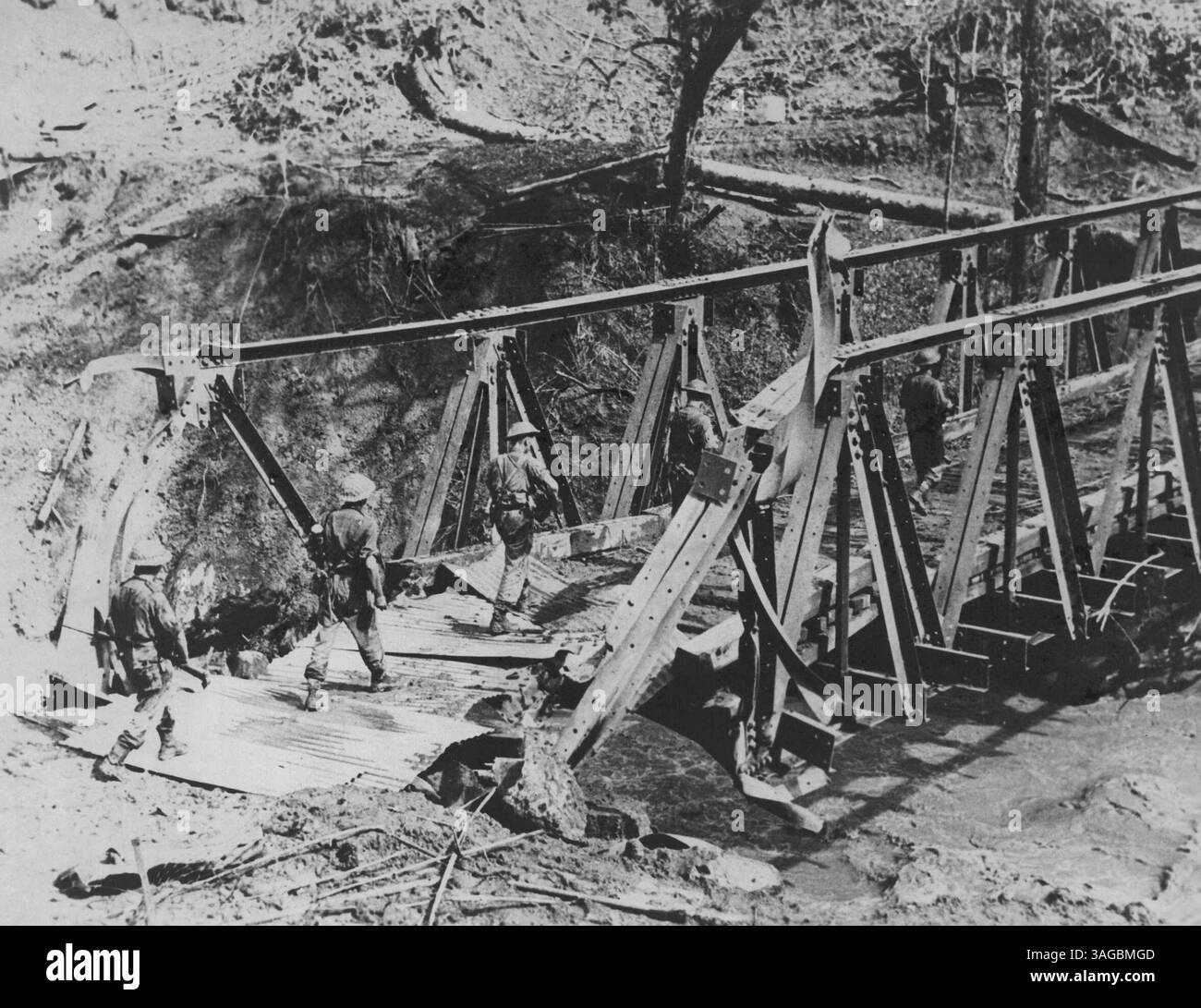 Monsoon Fighting On Burma Border -- Our forward troops in pursuit of the retreating enemy. Heavy rain, muddy roads and tracks and insect-infested jungles on the Assam Burma border have increased the difficulties of fighting the Japs. But both British and Indian troops remain undaunted and continue the pursuit of the enemy successfully. In hurried retreat the Japs tried to destroy this bridge on the Palel-Tamu road, but only small damage was done. July 01, 1951. (Photo by Interservices Public Relations Directorate (India)). Stock Photo