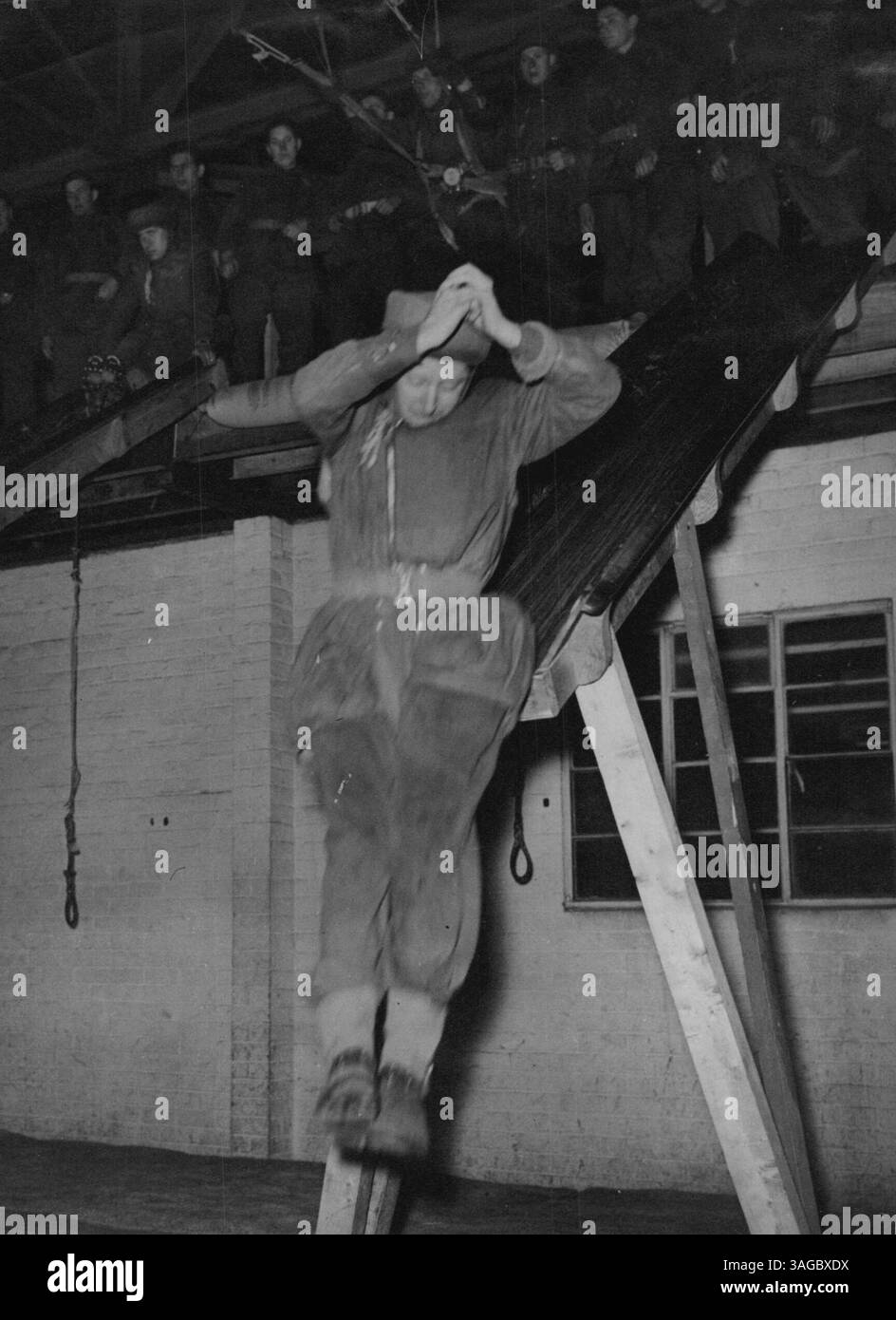 Training British Paratroops -- Coming off the landing shute; feet are together, hands above head, as if clasping the cords of a parachute.  Before making his first jump from an aircraft, the British paratroop soldier goes through a course of training in which more than 20 mediums are used to ensure perfection in two arts - jumping and landing. These pictures show British paratroops in training at a school in north-west England. February 01, 1945. (Photo by Planet News Ltd.). Stock Photo
