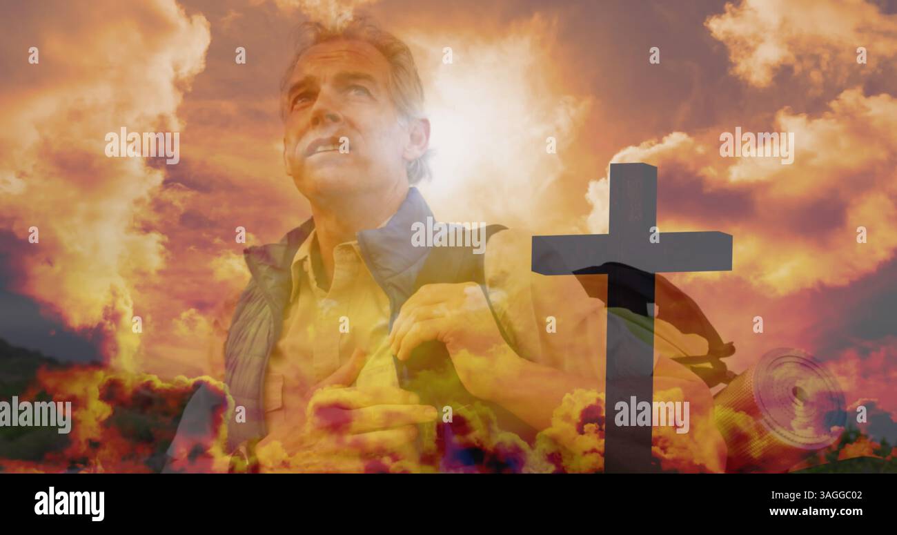 Senior caucasian man hiking over fast moving clouds and cross during sunset Stock Photo