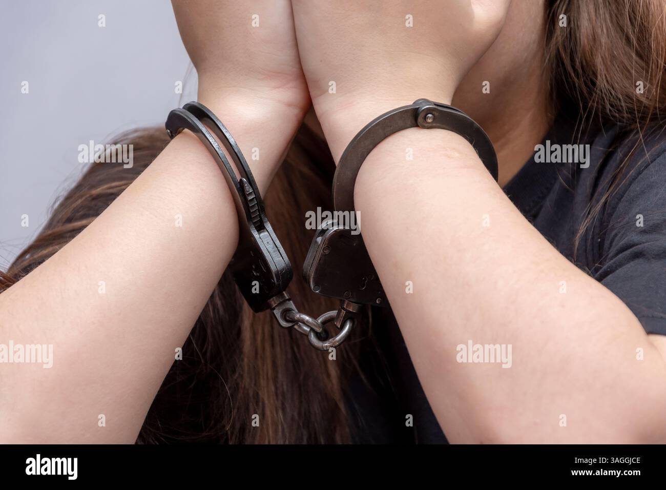 An emotional portrait of a young woman in handcuffs, gripped by anxiety Stock Photo