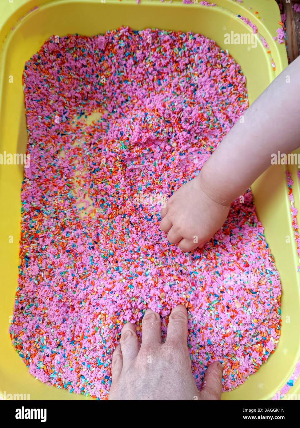 Mammy mother and baby play with touch dyed coloured rice in yellow ...