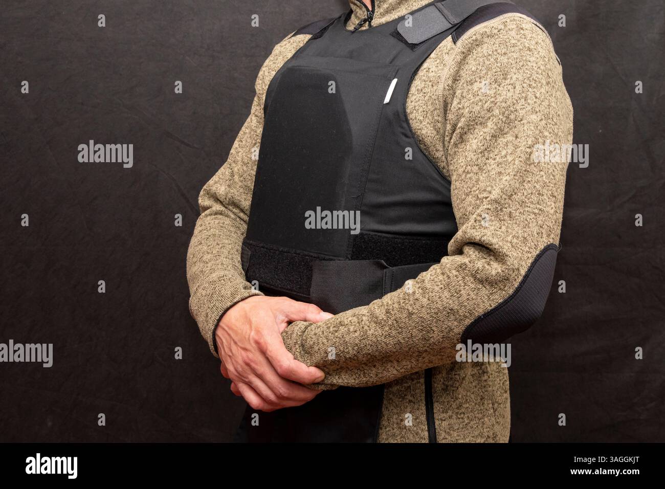 A muscular military man in a bulletproof vest on a black background ...