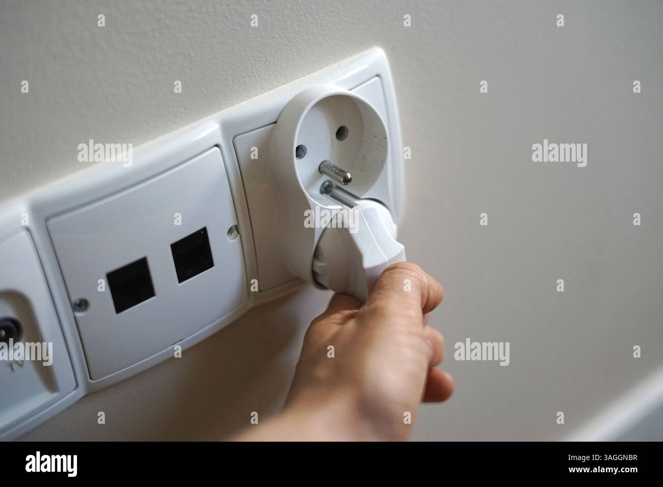 woman hand plug unplug put pulls cable cord from socket outlet charge ...