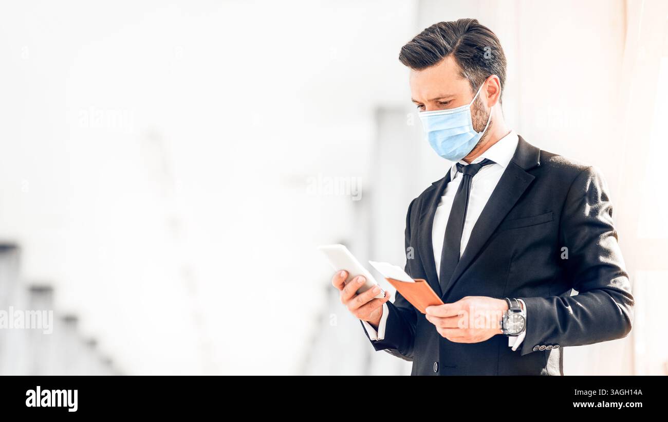 Entrepreneur in face mask using phone while waiting for flight Stock Photo