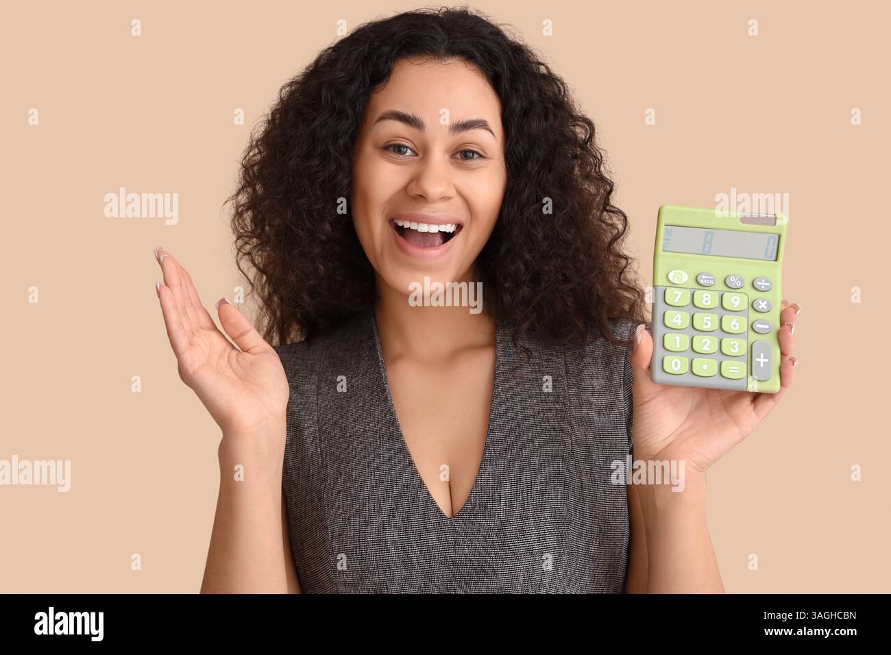 Young African-American woman with calculator on beige background Stock Photo