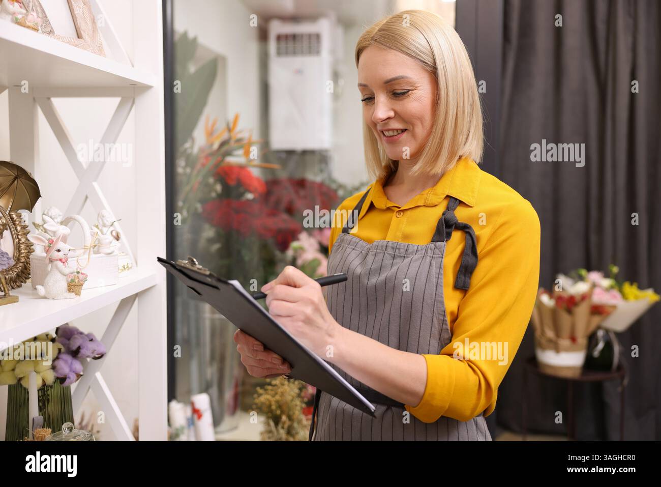 Business owner with clipboard taking notes in her flower shop Stock ...
