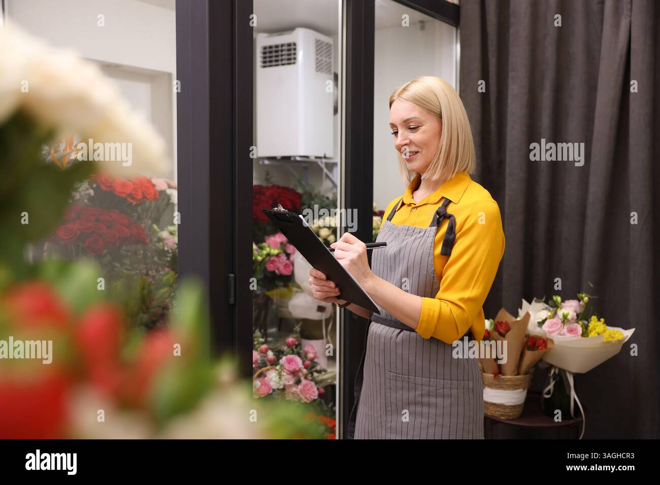 Business owner with clipboard taking notes in her flower shop Stock ...