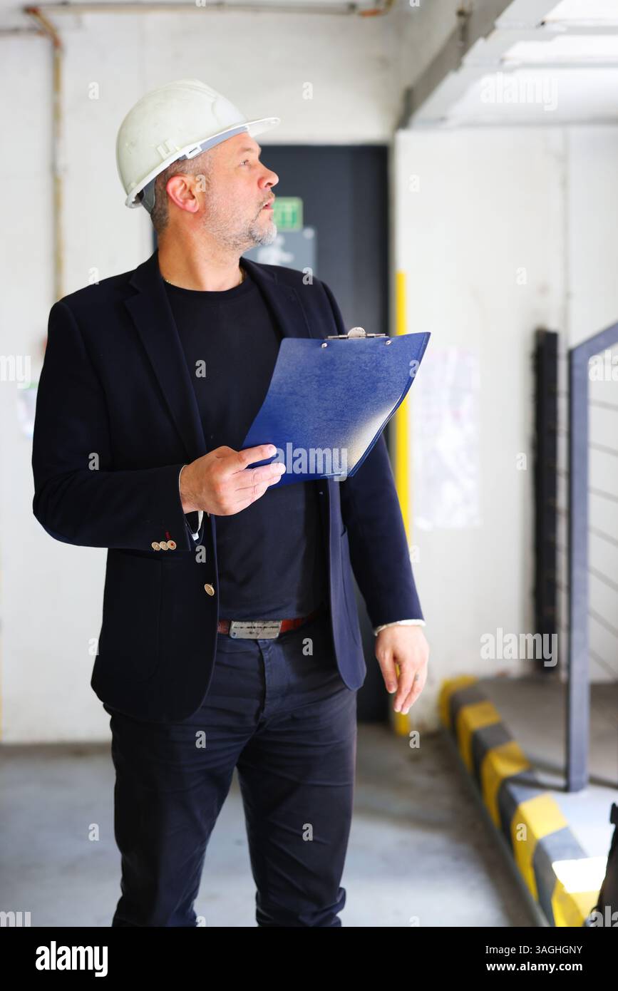 Building inspector with clipboard checking interior construction site for compliance. Stock Photo