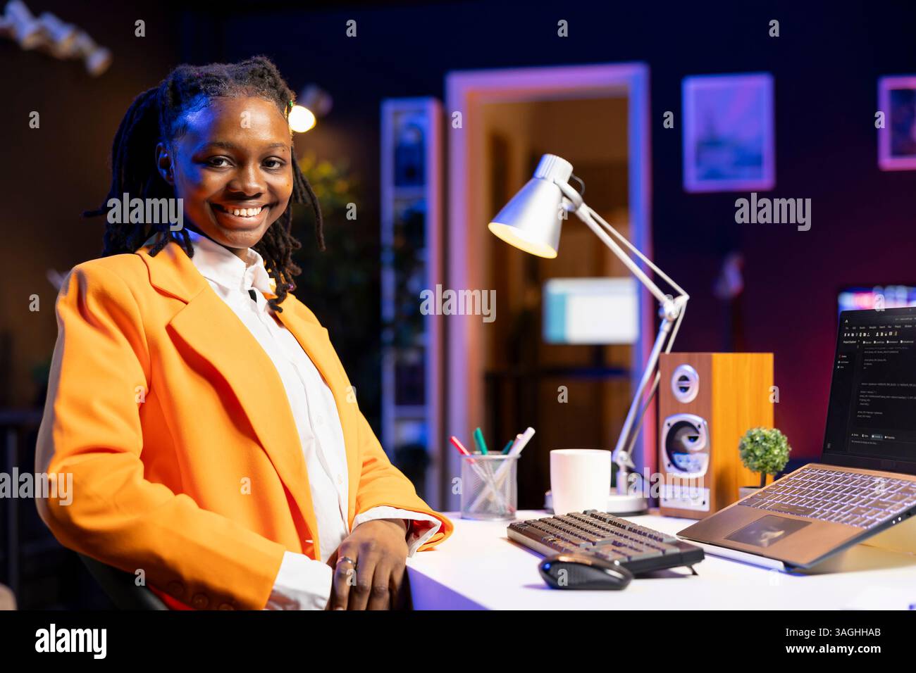 Portrait of smiling software developer writing code on laptop screen in apartment office using Java programming languages. Happy gen Z programmer remotely working from home, fixing database errors Stock Photo