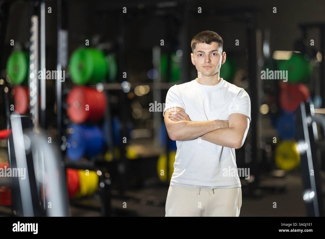 Athletic young man standing in gym with arms crossed Stock Photo