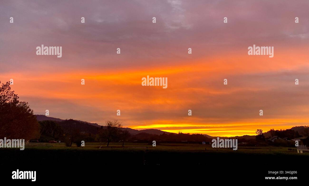 Fiery Sunset Over Rolling Hills Stock Photo