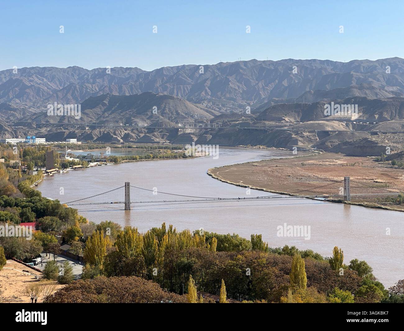 A stunning landscape featuring a bridge crossing a wide river with mountains in the distance. - Smartphone Captured Stock Image