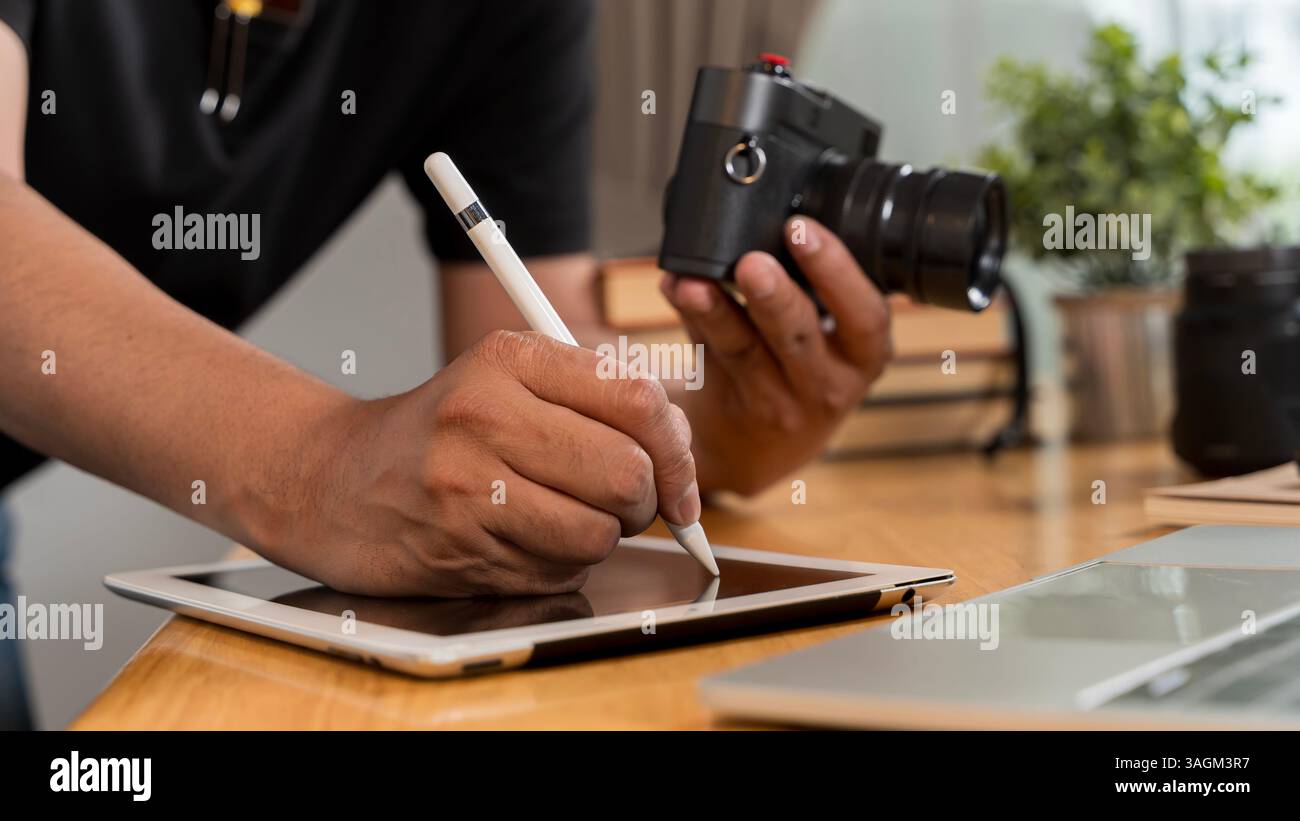 Close up of artistic hand using digital tablet and stylus while retouching image design at professional studio office desk. Woman doing editing work o Stock Photo