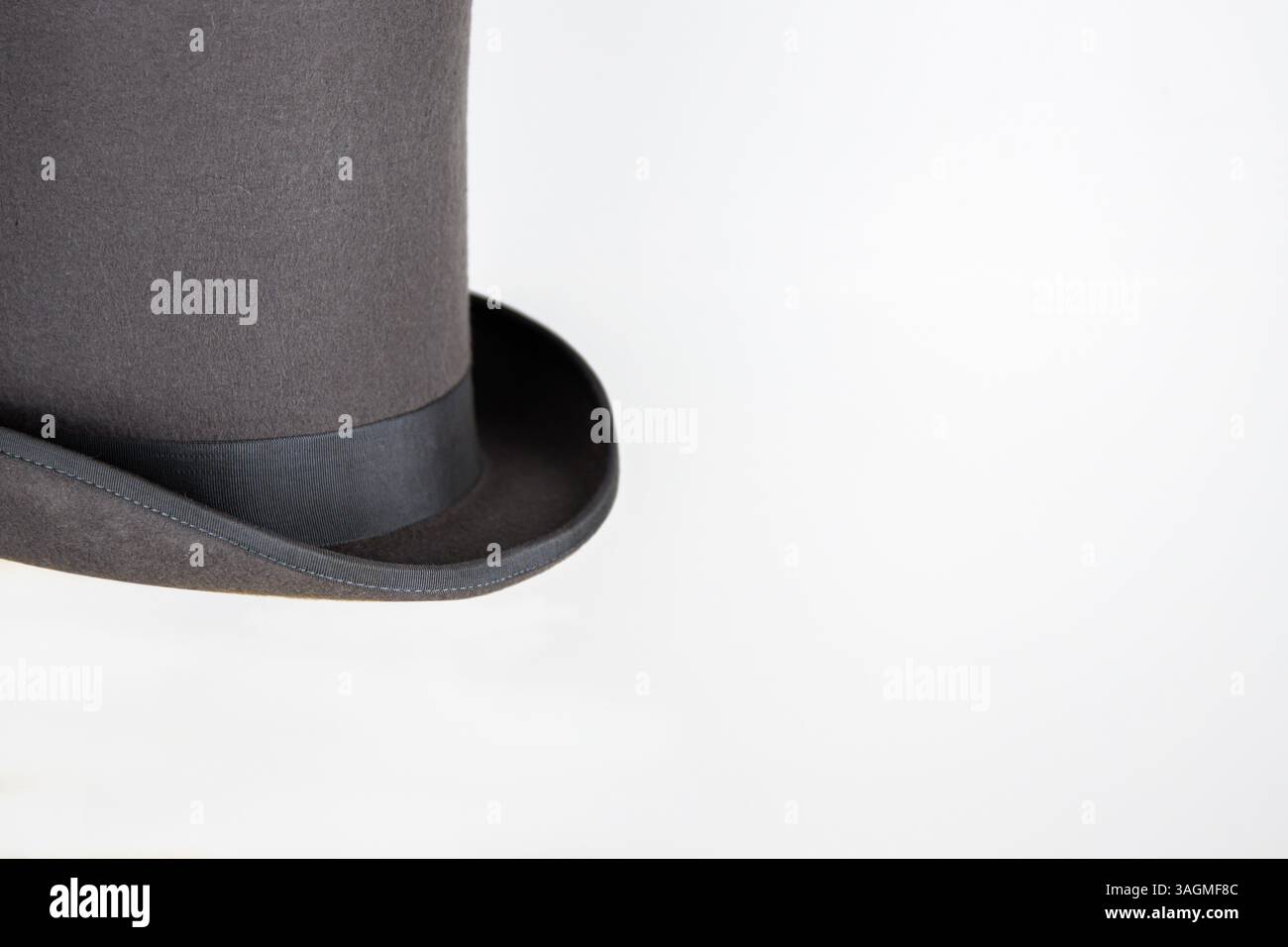 Magic hat. Topper. Elegant vintage gray beige wool felt top hat with black band on the wooden hat block. Grosgrain ribbon trim around rolled brim. Iso Stock Photo