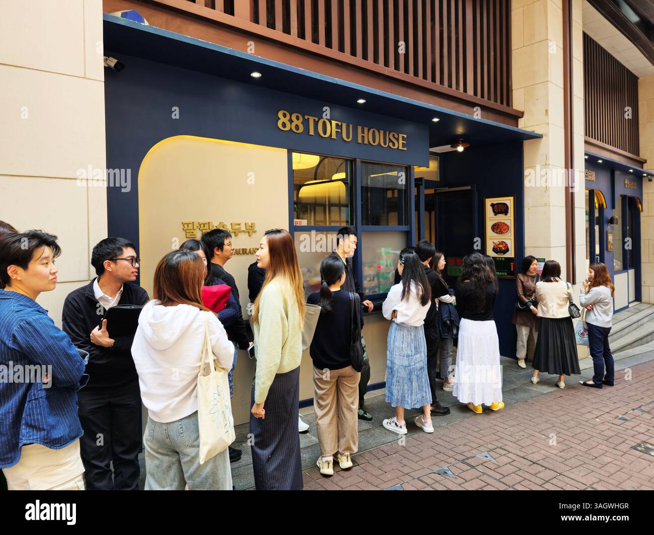 Customers waiting for a table at the popular 88 Tofu House on Welington street in Hong Kong. - Smartphone Captured Stock Image