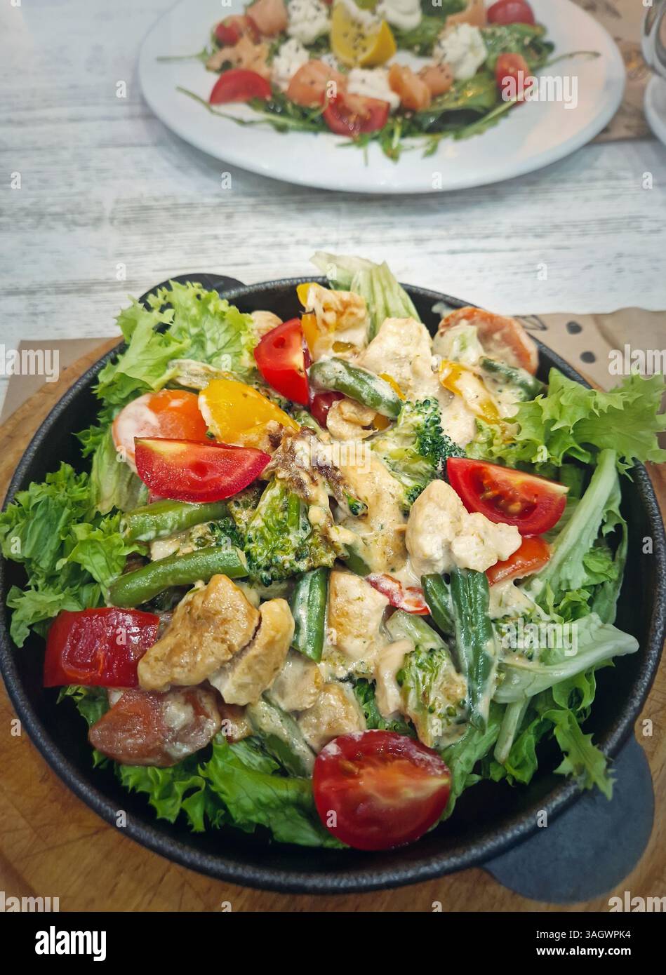 Closeup food plates in the restaurant with warm salad in the foreground - Smartphone Captured Stock Image