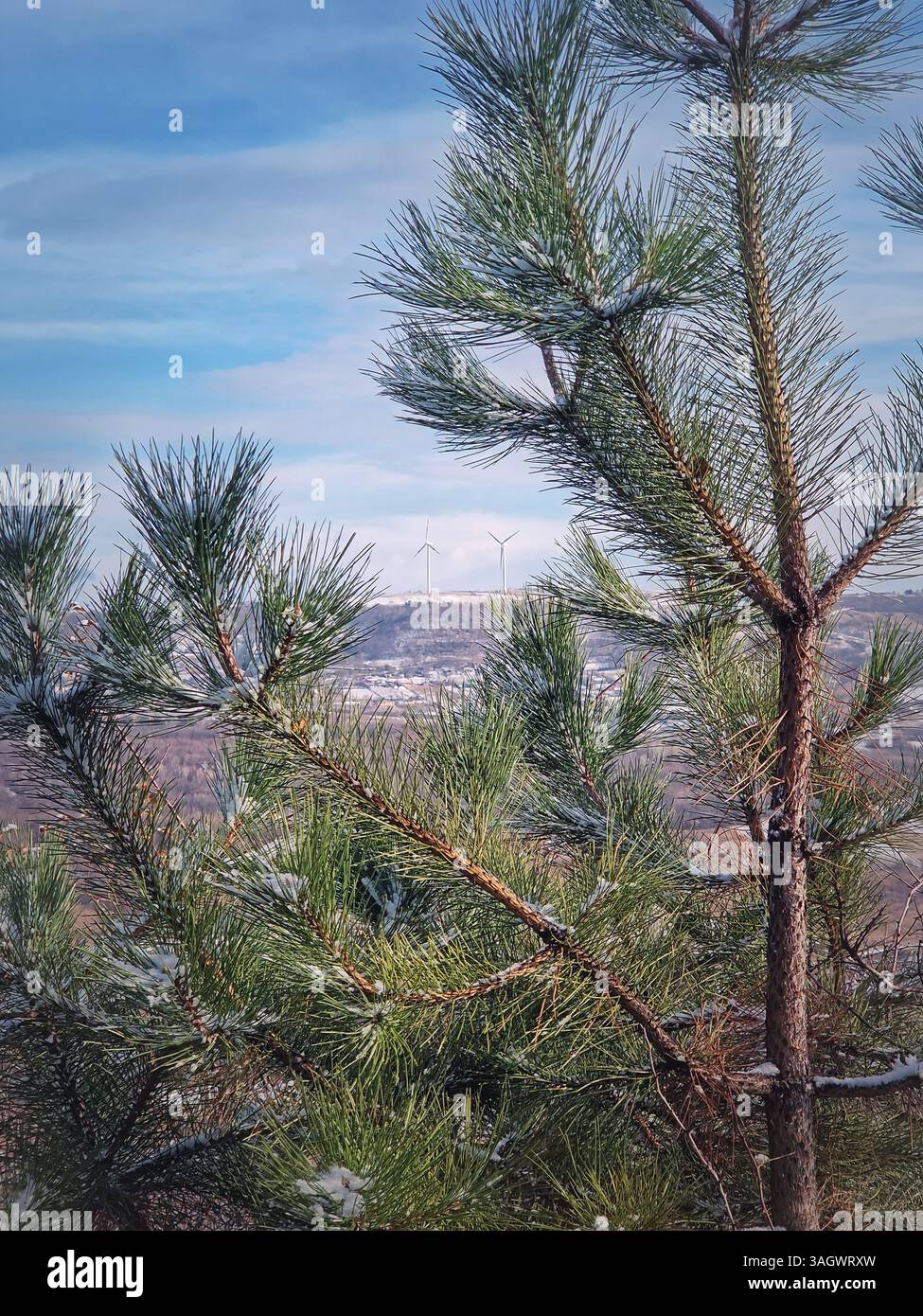 Wind turbines spinning on the top of the snowy countryside hills above the rural valley with small villages of Moldova - Smartphone Captured Stock Image