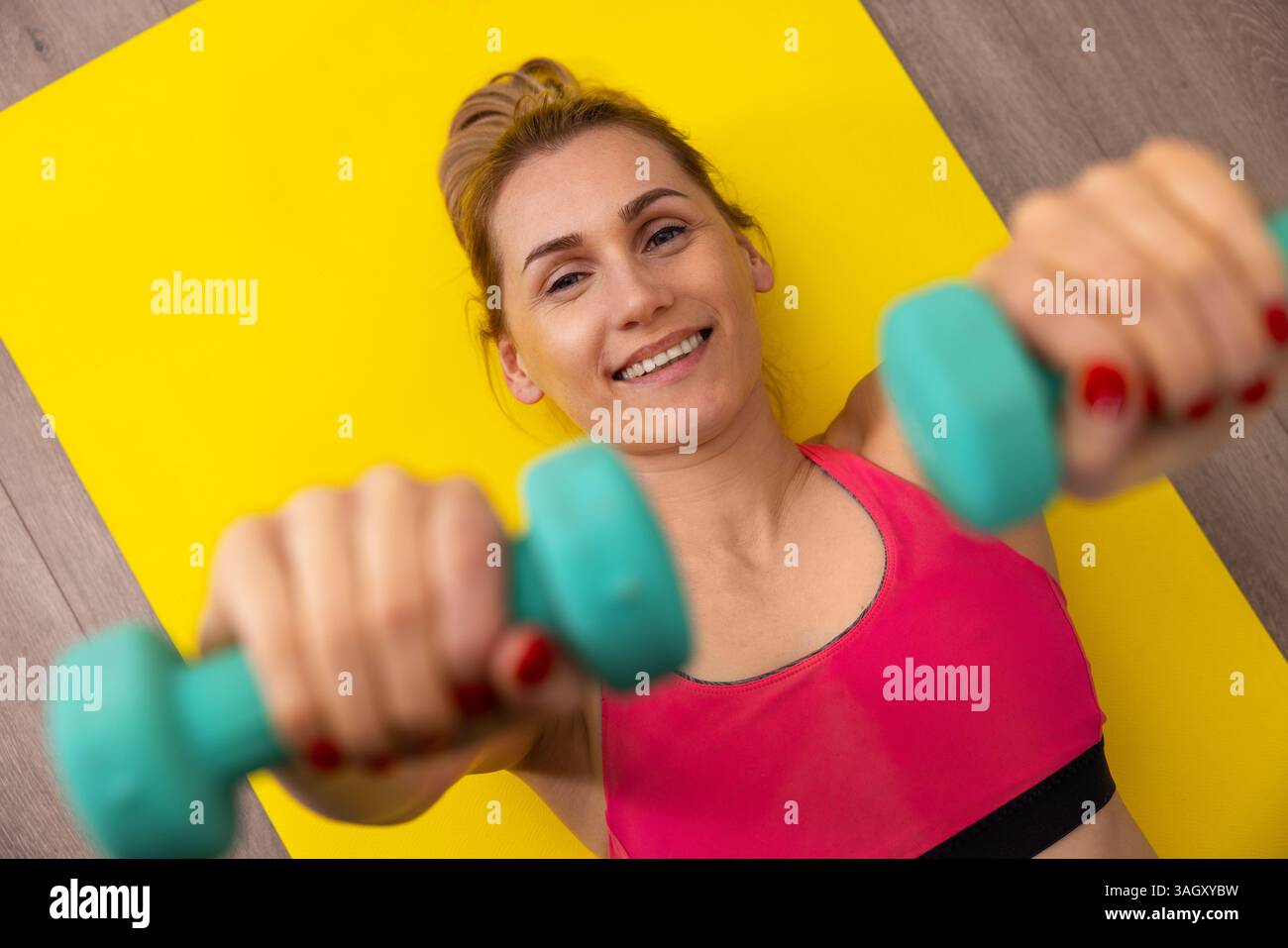 dumbbell exercises. woman is laying down on fitness mat and doing workout at home. top view Stock Photo