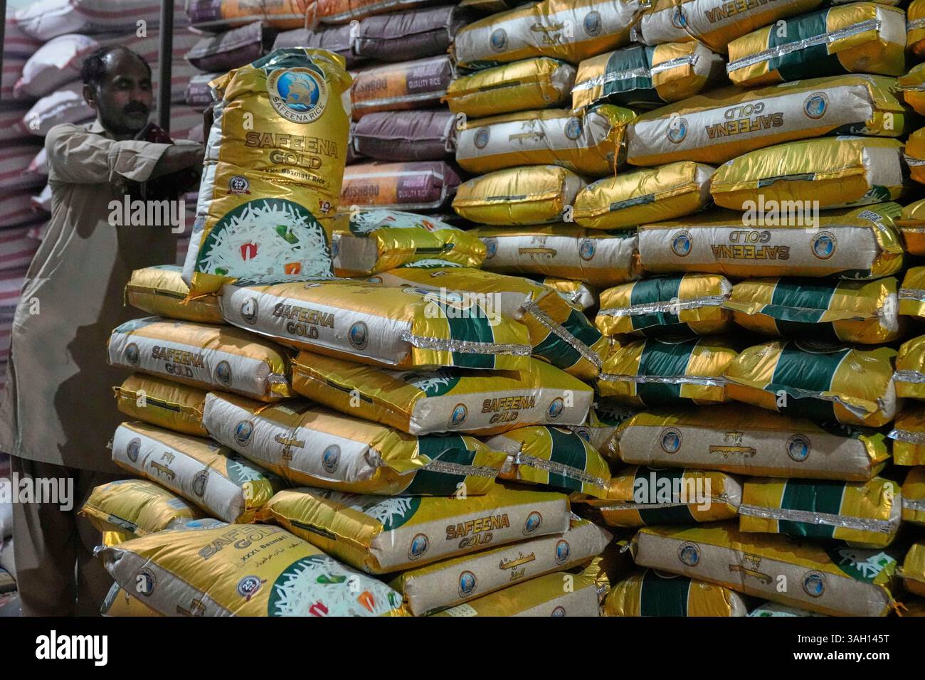 A laborer prepares to carry a sack of rice at a shop, in Lahore ...