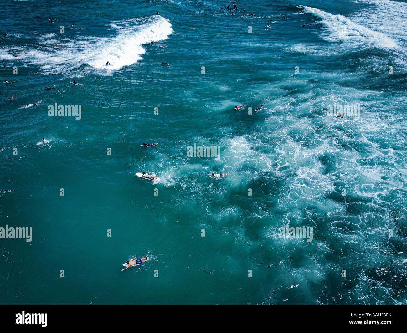 Aerial Drone View of Surfers Riding Waves in the Clear Blue Sea Near ...
