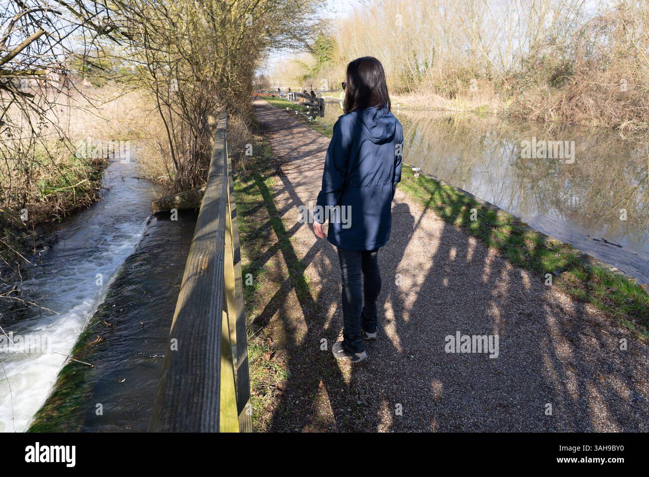 A woman looking at a rectangular side weir that is acting as flood relief for the Kennet & Avon canal near Aldermaston Wharf village, England Stock Photo