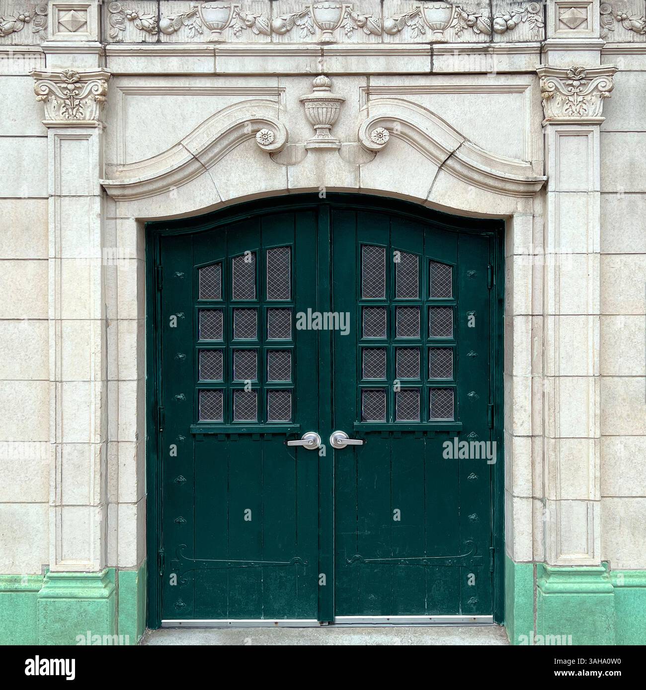 Ornate arched green doors set in an elaborately carved stone facade, featuring floral and classical motifs, in historic Chicago architecture - Smartphone Captured Stock Image