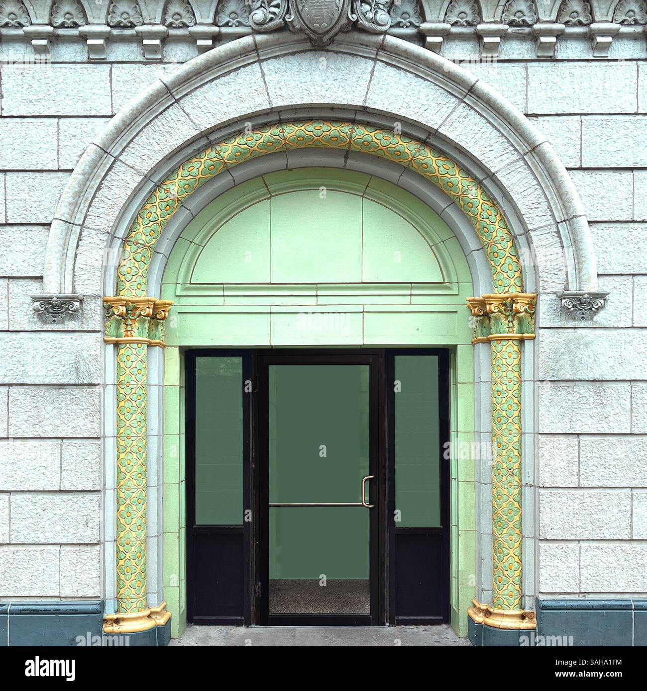 Elegant green arched door framed by intricately carved floral stone columns and a sculpted archway, set in a light stone facade in Chicago - Smartphone Captured Stock Image