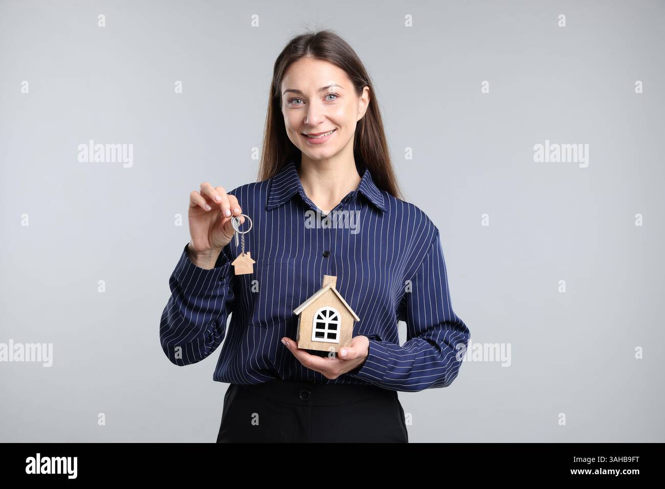 Real estate agent holding key with keychain and house model on light ...