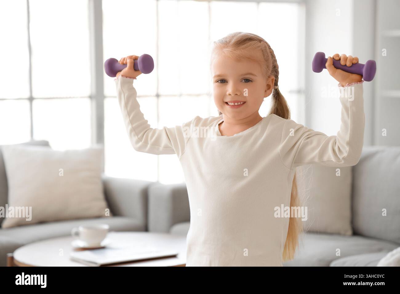 Sporty little girl with dumbbells training at home Stock Photo - Alamy