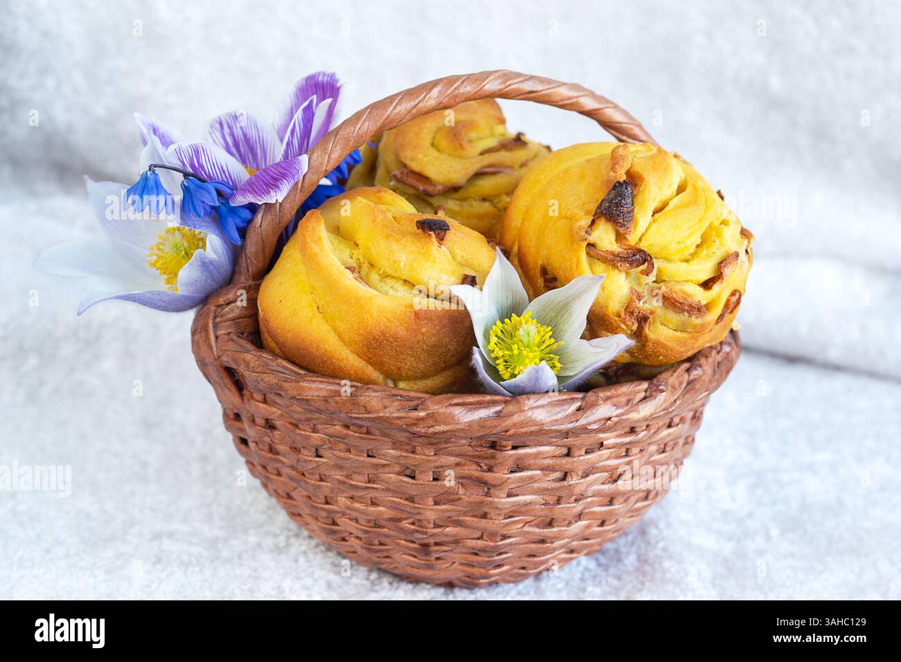 Small Easter cakes in a basket with flowers on a light background. Selective focus Stock Photo