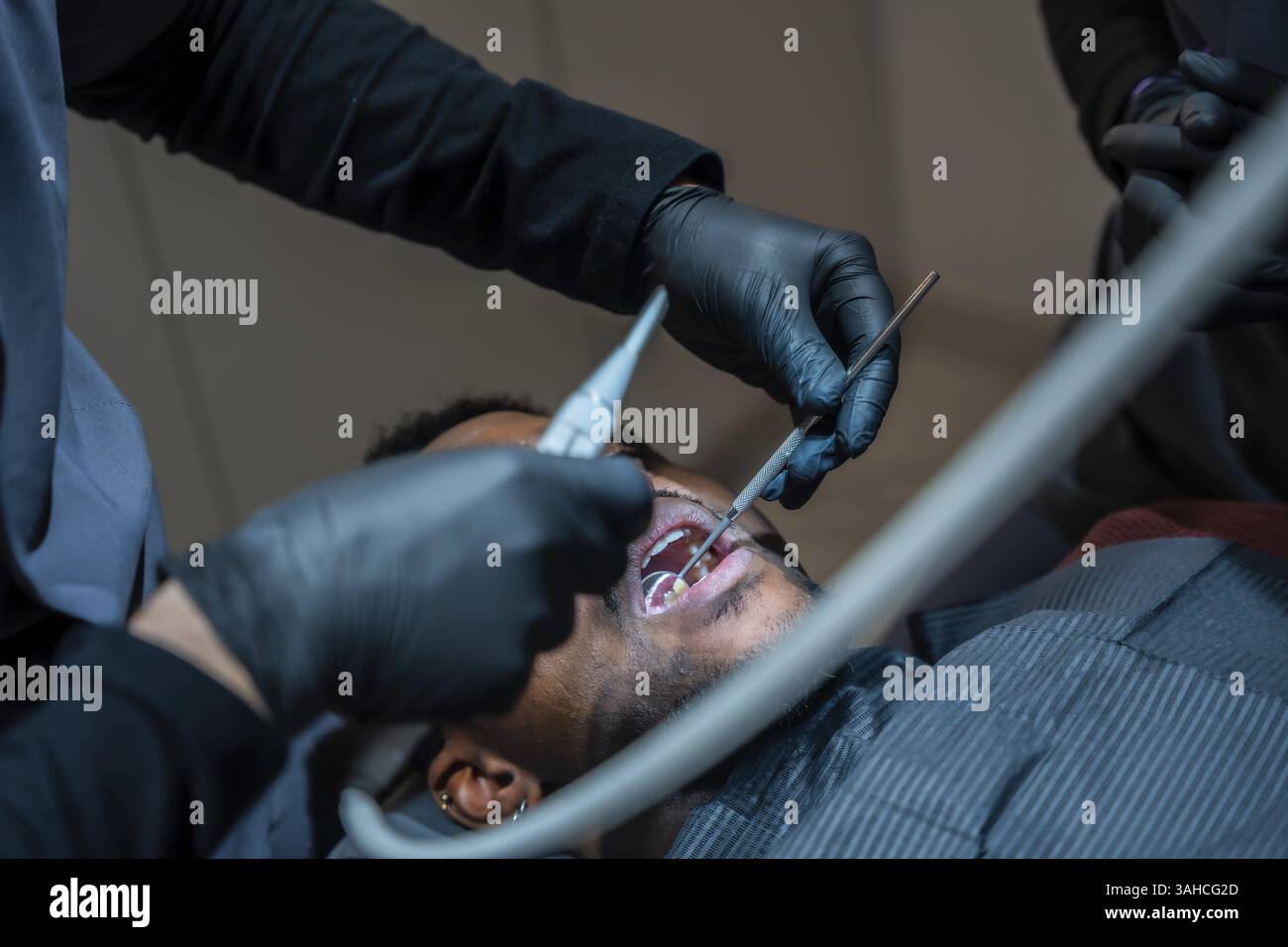 Dentist wearing black gloves examining patient's teeth with dental ...