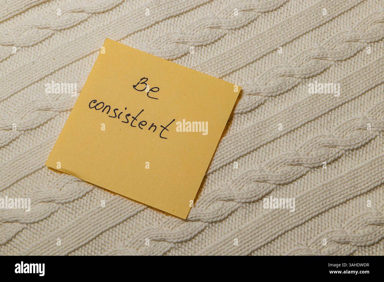 A handwritten note on a textured fabric background reads Be consistent ...