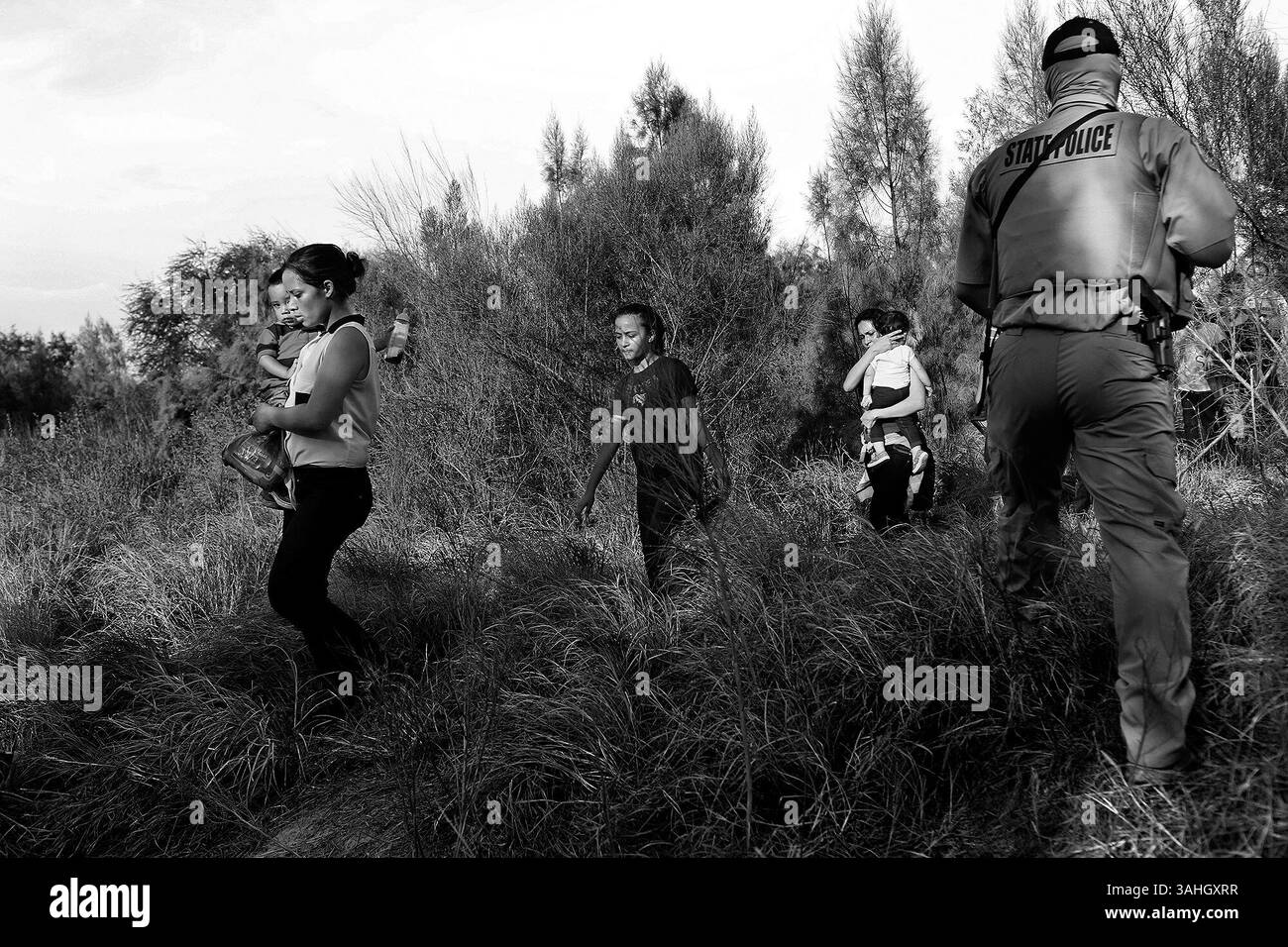 Aug. 13, 2014 - Mcallen - Central American immigrants including Maria Bertalina Ramirez, 21, left, of Honduras, with her son, Jose Joel, 1, are guided by Texas Game Wardens and a U.S. Border Patrol agent after they crossed the Rio Grande River by boat into the United States on Wednesday, August 13, 2014. The group of 14 was questioned and taken in vans to be processed. (Credit Image: © San Antonio Express-News/ZUMA Wire) Stock Photo
