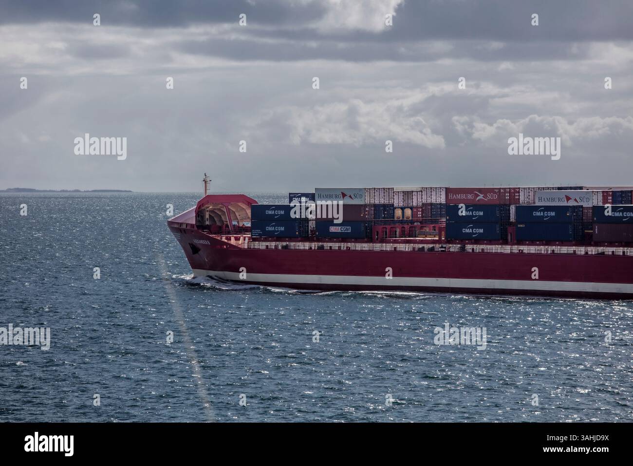 Cargo ship carrying containers navigates through calm ocean waters ...