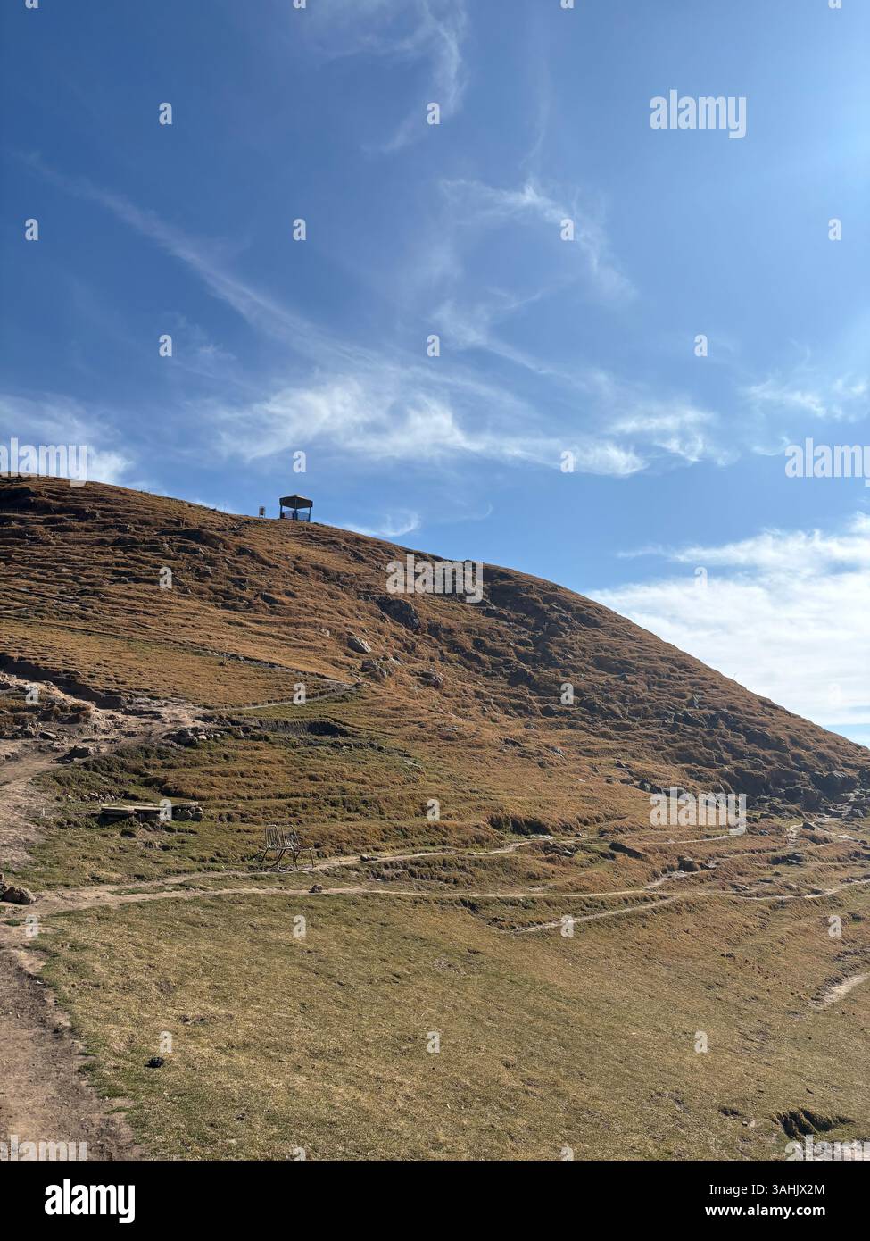 Hilltop Trail Under Bright Blue Sky With a Small Hut in Distance - Smartphone Captured Stock Image