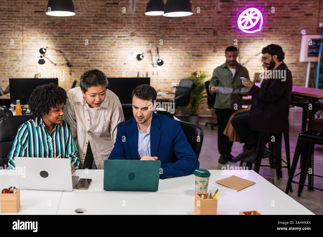 Multi ethnic team collaborating on laptops in modern office Stock Photo