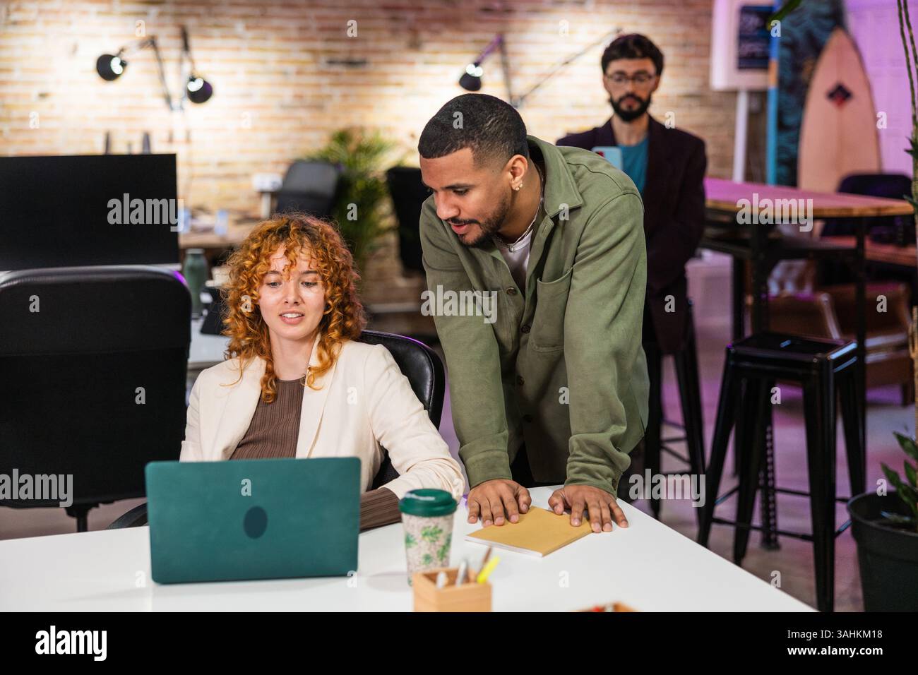 Multi ethnic team collaborating on laptop in modern office Stock Photo