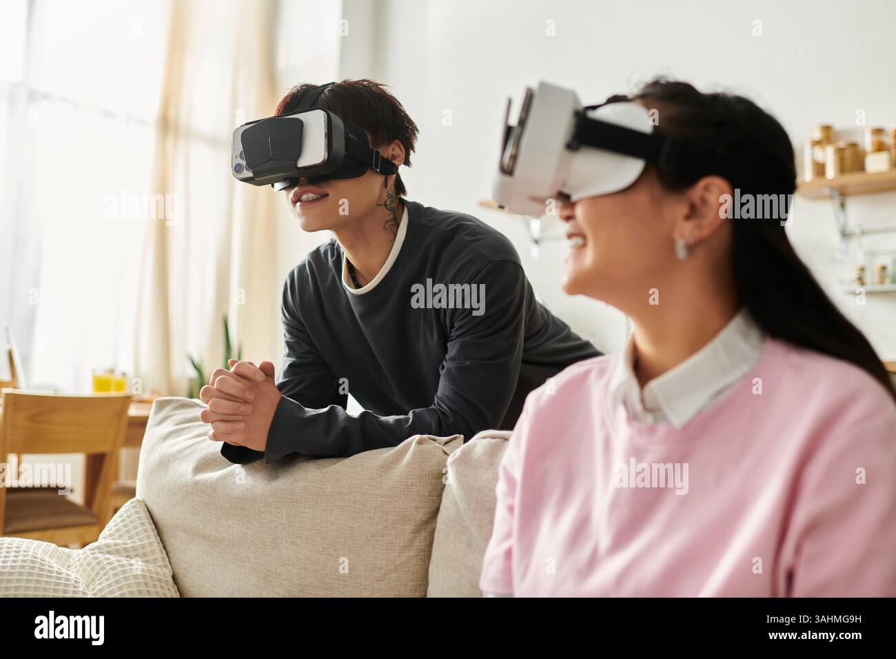 Sharing smiles and adventures, a young asian couple enjoys virtual reality experiences together. Stock Photo