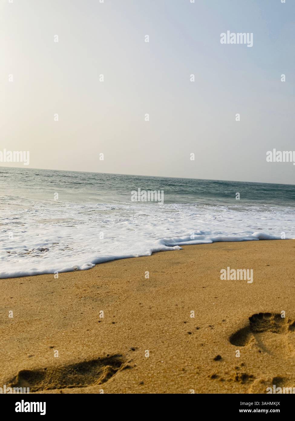 A serene beach view with soft, golden sand stretching into the distance, interrupted only by the delicate footsteps of someone who recently passed - Smartphone Captured Stock Image