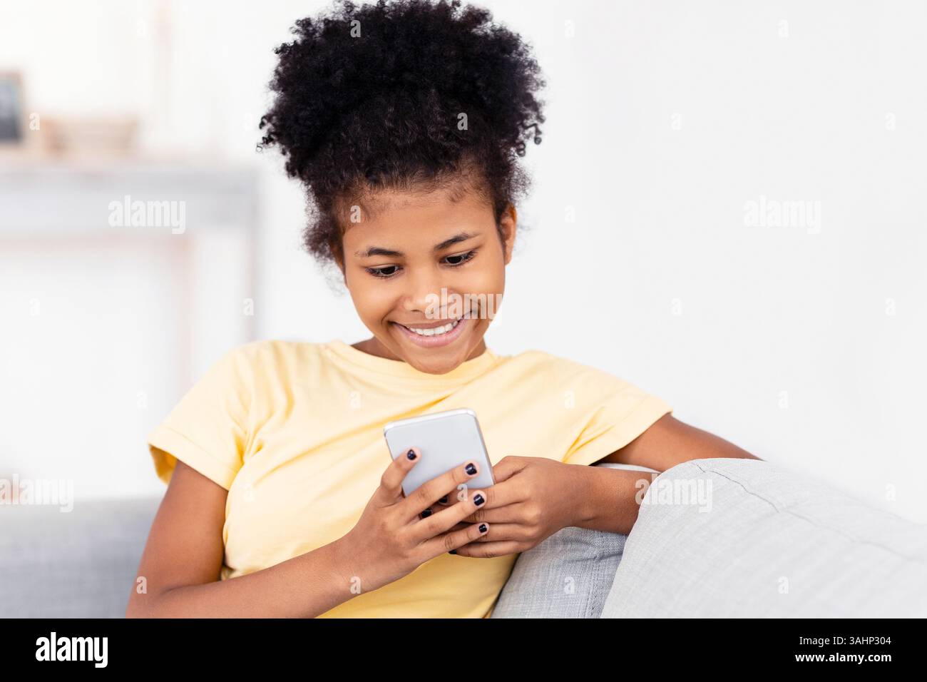 Happy Teen Girl Using Phone Sitting On Sofa At Home Stock Photo - Alamy